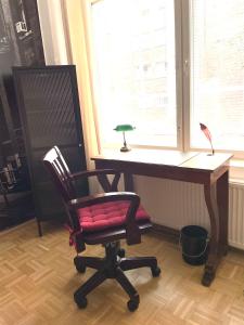 einen Schreibtisch mit einem roten Stuhl neben einem Fenster in der Unterkunft Loft in an old factory in Turku