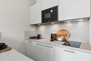 Home and CoLiving Bonn I Aparthotel I Soft Opening في بون: مطبخ مع دواليب بيضاء وميكرويف