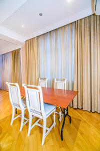 a dining room with a wooden table and white chairs at Deluxe Apartment 142/43 in Baku