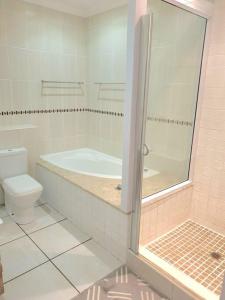 a bathroom with a tub and a toilet and a shower at Modern 2Bedroom Self Catering unit HBos. in Mossel Bay