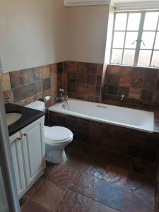 uma casa de banho com um WC, uma banheira e um lavatório. em Redberry Guest House em Mbabane