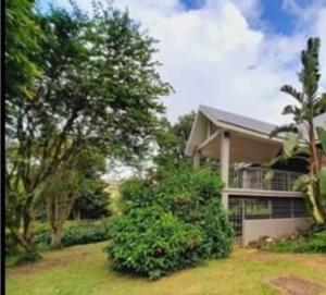 una casa con árboles y arbustos delante de ella en Redberry Guest House, en Mbabane