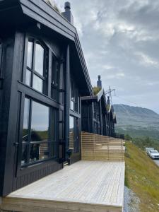 ein schwarzes Haus mit einer Holzterrasse und einer Terrasse in der Unterkunft Gaustablikk Sportshytte in Rjukan