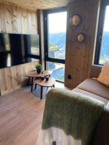 a living room with a couch and a tv and a table at Gaustablikk Sportshytte in Rjukan