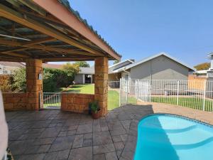 un patio trasero con piscina y pérgola en Midway Overnight Rooms, en Kimberley