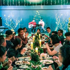 a group of people sitting around a table with christmas lights at Villa anugerah hill in Tomohon