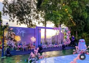 a stage with purple and pink flowers and tables and chairs at Villa anugerah hill in Tomohon