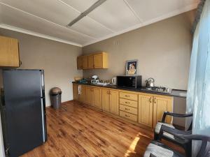 a kitchen with a black refrigerator and wooden cabinets at Midway Overnight Rooms in Kimberley
