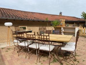 a wooden table and chairs in front of a building at Maison sur cour et véranda in Courzieu