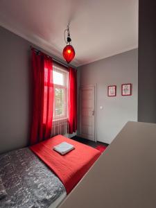 a bedroom with red curtains and a bed with a laptop on it at Apartament Na Chłodnej | The High Street in Suwałki