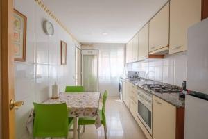a kitchen with a table and green chairs at Apartamento en complejo residencial, con piscina. in Salou