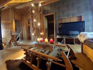 a living room with a table and a tv and candles at Buckey Lodge, à 2 minutes des cascades de Tendon in Tendon