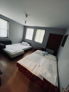 two beds in a room with two windows at Cottage House Official in Niš