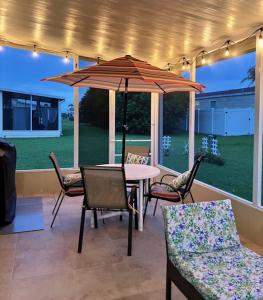 un patio con mesa, sillas y sombrilla en Coastal Imagination Oasis, en Davenport