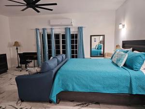 a bedroom with a large bed with a blue bedspread at Roots Cafe Rooms in Negril