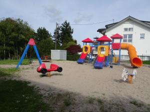 einen Spielplatz mit bunten Spielgeräten im Sand in der Unterkunft Haus Fermate in Wilhelmsfeld
