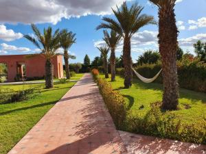 a pathway with palm trees and a hammock in a yard at Dar Lalla Mhalla Villa 975m2 5ch - Rt de Fes in Marrakesh