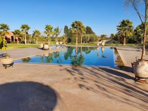 a pool of water in a park with palm trees at Dar Lalla Mhalla Villa 975m2 5ch - Rt de Fes in Marrakesh