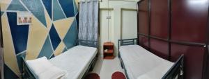 a small room with two beds and a wall at JoyNest Guest House in Patna