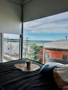 una taza de café sentada en una mesa frente a una ventana en AZUL - Pto Madryn, en Puerto Madryn