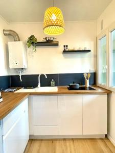 - une cuisine avec des placards blancs, un évier et une lampe dans l'établissement L'Open d'Australie, à Chalon-sur-Saône