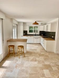 Una cocina con una encimera y dos taburetes en ella. en Maison en Normandie - 5 min plage Houlgate - Villers sur mer, en Auberville