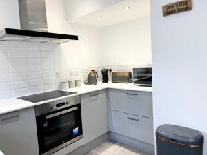 een keuken met witte kasten en een fornuis met oven bij Saltwater Pearl - A charming 4 bed townhouse in Ilfracombe