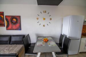 Pandora apartment في لاس غاليتاس: طاولة طعام مع كراسي وساعة على الحائط