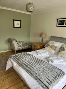 a bedroom with a large bed and a chair at Loch Lomond Apartment in Alexandria