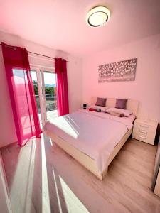 a bedroom with a large bed and a window at Holiday house "Sabine pink" in Skrbčići