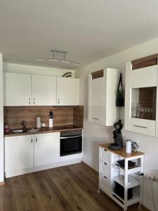 eine Küche mit weißen Schränken und einem Holztisch in der Unterkunft Ferienwohnung Traumwerk Titisee in Titisee-Neustadt