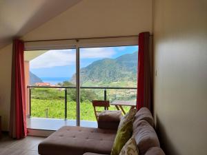 a living room with a couch and a large window at Matilde House in São Vicente