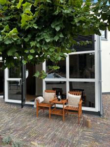 dwa krzesła i stół przed oknem w obiekcie Bed en Baguette w mieście Burgh Haamstede