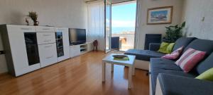 Una sala de estar con un sofá azul y un televisor en Sentona Apartment, en Rijeka