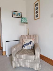 a chair with a pillow in a living room at The Little House, Wadebridge, Cornwall in Wadebridge