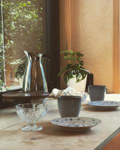 a table with bowls and plates on it with a vase at Elevated Tiny House Glamping in Tjøme