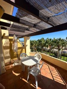 Una mesa y sillas en un balcón con palmeras. en Canela Park frontal al mar, en Isla Canela 7 fotos más