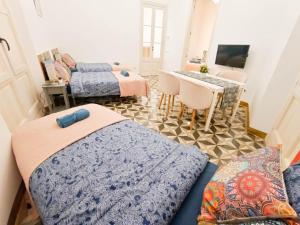 a bedroom with two beds and a table and a desk at By Liceu Rooms in Barcelona