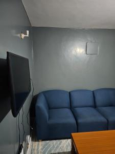 a blue couch in a living room with a tv at West Homestays Kodi2518 in Nairobi