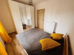 1 dormitorio con 1 cama y 2 almohadas amarillas en Apartament Neustettin-Polna Szczecinek, en Szczecinek