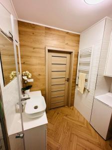 Apartament Neustettin-Polna Szczecinek في شتيتشينيك: حمام مع حوض أبيض وجدران خشبية