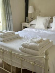 Una cama blanca con toallas encima. en Gorgeous Cottage in Skirmett with Parking en Henley on Thames