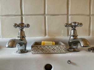 a bathroom sink with two faucets and a soap holder at Gorgeous Cottage in Skirmett with Parking in Henley on Thames
