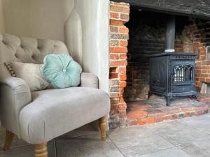 a chair in front of a fireplace with a stove at Gorgeous Cottage in Skirmett with Parking in Henley on Thames