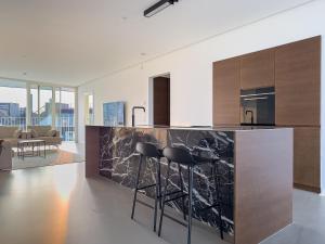 a kitchen with a black marble counter and stools at Exclusive Penthouse with Sunset Views in Copenhagen