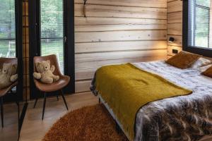 um quarto com uma cama e dois ursos de peluche numa cadeira em Upea Villa Lapin Kulta hirsihuvila Inarijärven rannalla em Inari