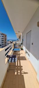 a balcony with chairs and tables on a building at Vilamoura-Quarteira Beaches Apt with pool and sea view in Quarteira