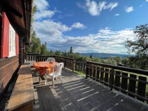 una terraza de madera con mesa y sillas. en Elveseter - log cabin with an amazing view, en Lunde