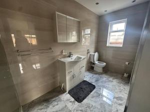 ein Bad mit einem Waschbecken, einem WC und einem Fenster in der Unterkunft Exquisite Luxury Studio in Mitcham