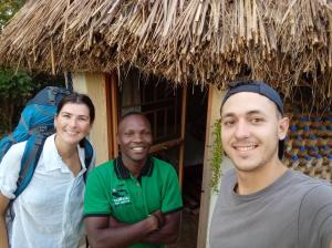 un gruppo di tre persone che si trovano davanti a una capanna di Plastic Bottles House a Entebbe